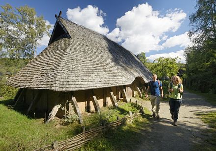 Mensen naast het longhouse in het openluchtmuseum Oelringhausen